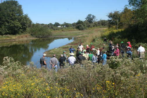 group of people by a pond hearing talk about pond management